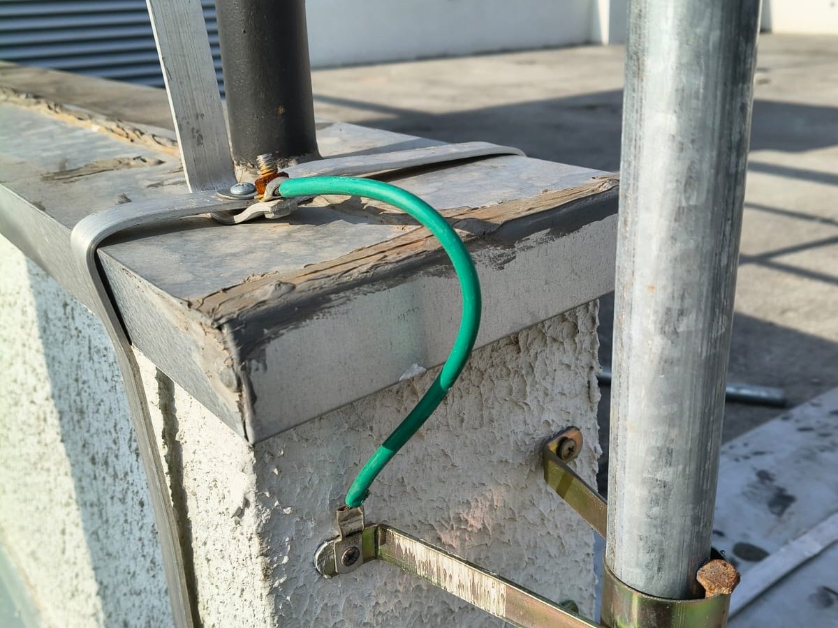 Ligação equipotencial em cabo verde entre estrutura metálica e o rufo da platibanda na cobertura de um edifício