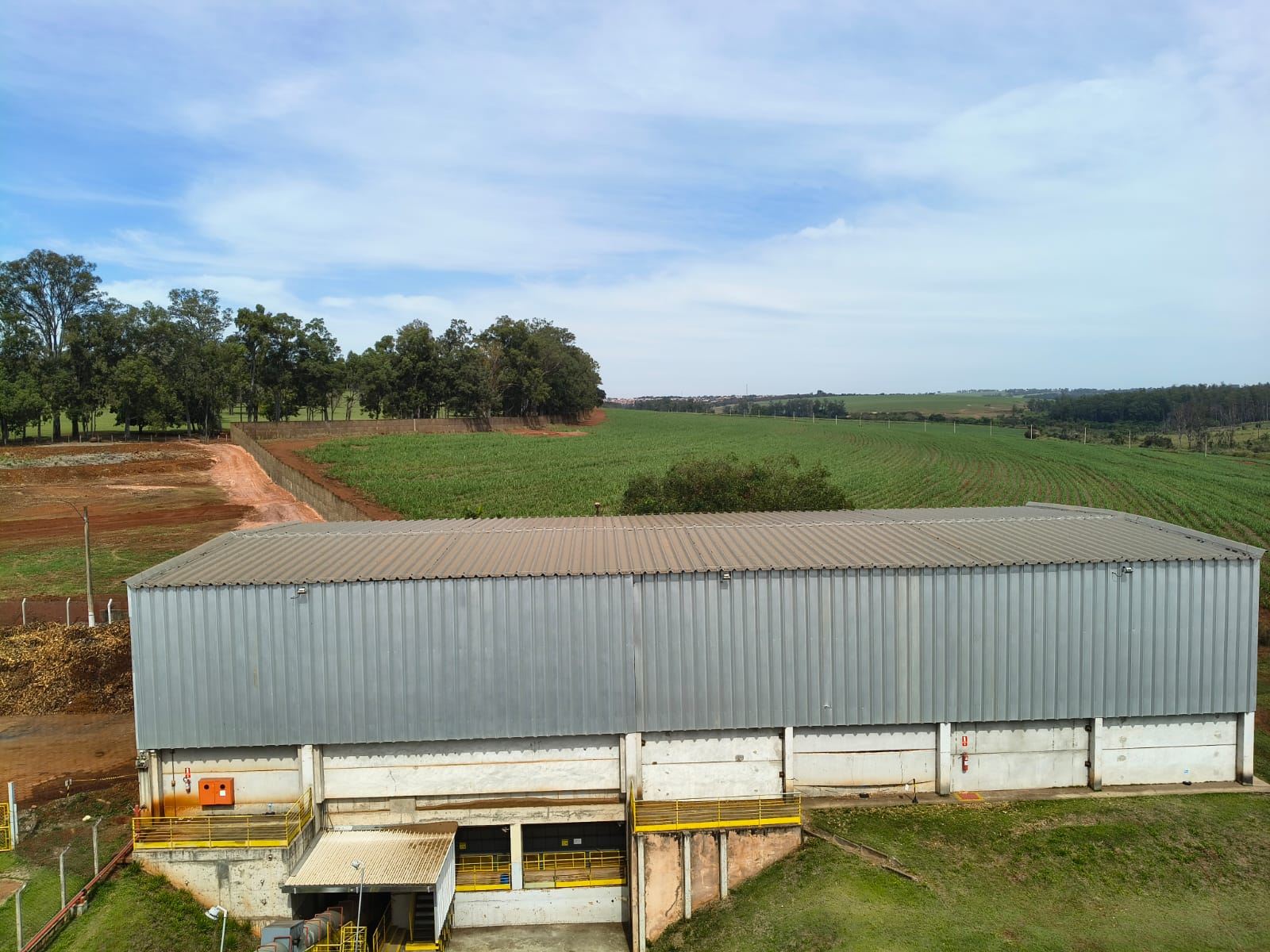 Galpão metálico rural com lavoura ao fundo