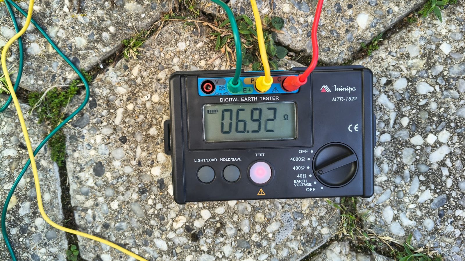 Terrômetro digital indicando 6,92 ohms durante medição de resistência de aterramento, com os cabos de ensaio conectados sobre o piso