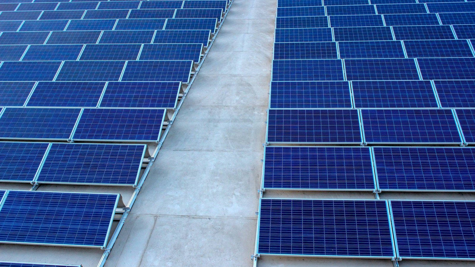 Fileiras de módulos fotovoltaicos instalados sobre laje de concreto, com corredor de circulação entre elas
