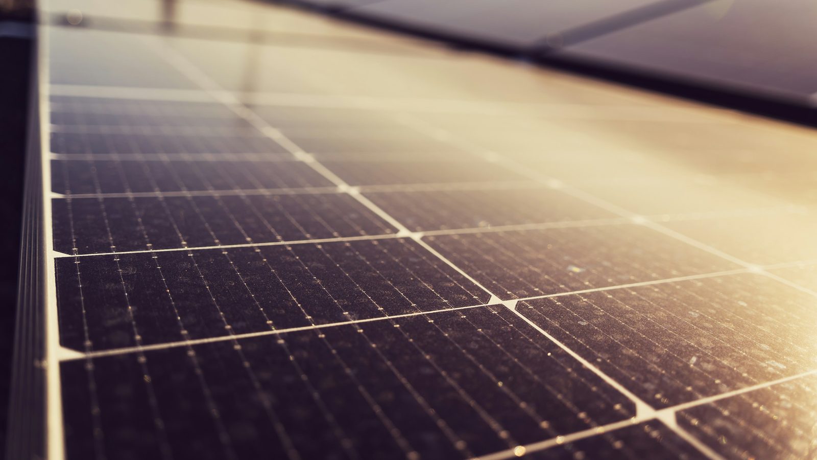 Módulos fotovoltaicos em cobertura, vistos de perto, com poeira acumulada sobre o vidro das células
